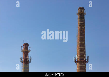 Old tower and pipe production on the background of blue sky. Stock Photo