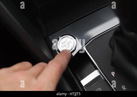 Driver hand pushes engine start stop button. Modern luxury crossover car interior details Stock Photo