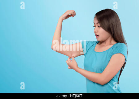 Young asian woman losing muscle on her arm on blue background Stock Photo
