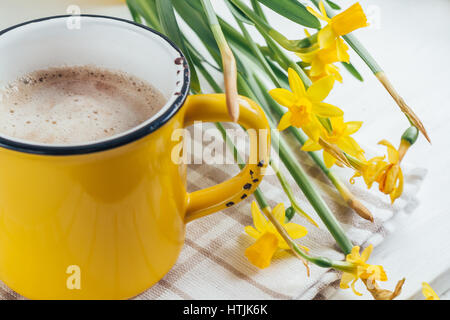 Spring flowers daffodils with a cup of coffee, cappuccino and close-up Stock Photo