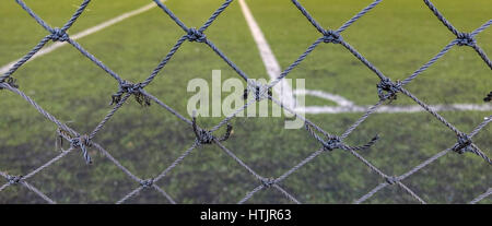 Front focus of the thin mesh fence barrier between us and the football field. Stock Photo