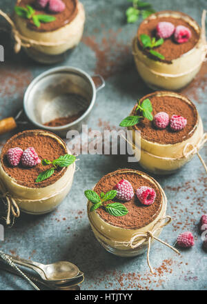 Homemade Tiramisu in individual glasses with frozen raspberries and mint Stock Photo