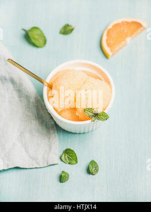 Pink grapefruit sorbet with fresh mint leaves in white bowl Stock Photo