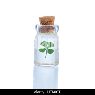 Sealed glass bottle holding single four leaf clover isolated on white with reflection. Luck in bottle concept for St. Patrick Day. Stock Photo