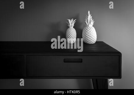 A contemporary console table - made out of charred wood according the shou-sugi-ban Japanese technique - supporting two porcelain pineapples. Stock Photo
