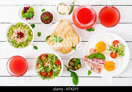 English breakfast - fried egg, tomatoes and bacon. Breakfast for two. Oatmeal. Flat lay. Top view Stock Photo