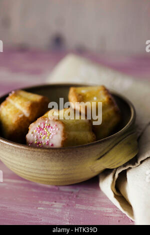 Traditional Polish babka - Easter mini cakes with icing and pink sprinkles. Stock Photo