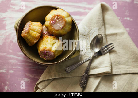 Traditional Polish babka - Easter mini cakes with icing and pink sprinkles. Stock Photo