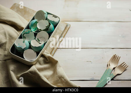 Plate full of blue tinted eggshells on white wooden table. Easter decoration. Stock Photo