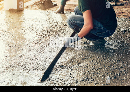 plasterer concrete worker at floor of house construction Stock Photo