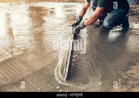 plasterer concrete worker at floor of house construction Stock Photo