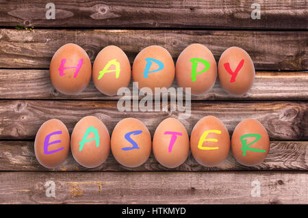 Happy easter written on eggs on wooden planks background Stock Photo