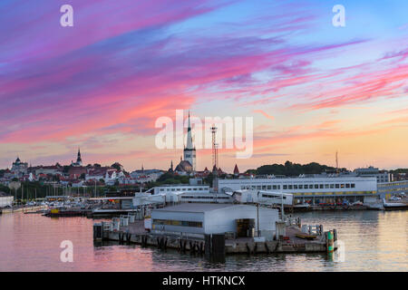 Evening panorama of Tallinn at sunset. View from ferry on sea terminal passenger port and old town architecture with high spire on Church of St. Olaf. Stock Photo