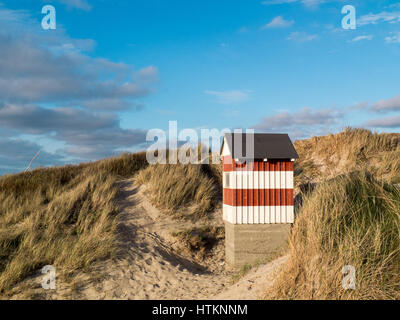 Small red and white striped hut standing on the beach dunes with sea views Stock Photo