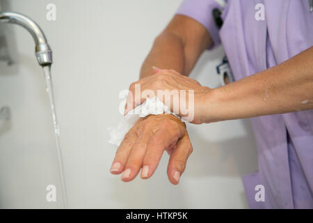 Drying hands with a paper towel in clinical setting Stock Photo