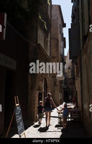 Mother walking with two young children in summery street scene in Pézenas, South of france Stock Photo