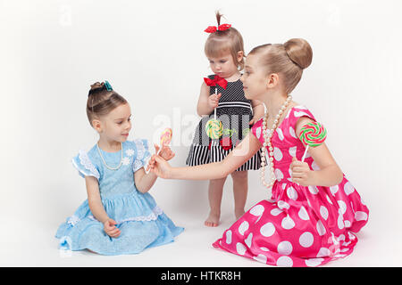 The girl treats her younger sisters big beautiful lollipops Stock Photo