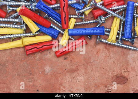 Plastic Dowels ans Screws on Red Brick Background Stock Photo
