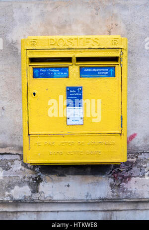 A yellow French post box hangs on a wall in Paris France. Stock Photo