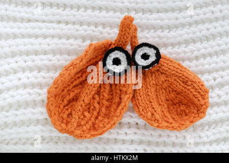 Humor eyes of winter from yarn, diy simple background for Xmas holiday by knitted leaf for eyebrows, nose on white scarf background, funny face craft Stock Photo