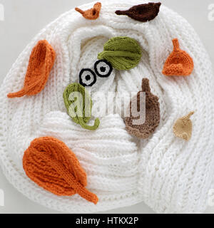 Humor eyes of winter from yarn, diy simple background for Xmas holiday by knitted leaf for eyebrows, nose on white scarf background, funny face craft Stock Photo