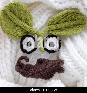 Humor eyes of winter from yarn, diy simple background for Xmas holiday by knitted leaf for eyebrows, nose on white scarf background, funny face craft Stock Photo