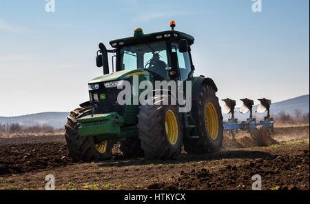 Varna, Bulgaria - March 5, 2017 Ploughing a field with John Deere tractor. John Deere was manufactured in 1995-1999 and it has JD 7.6L or 8.1L 6-cyl d Stock Photo