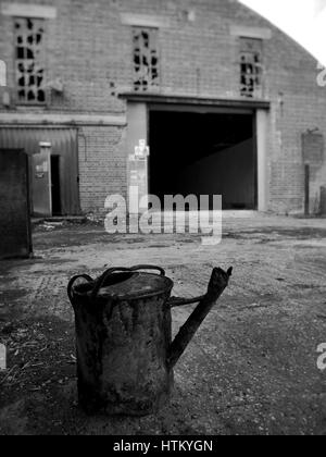 Rusty watering can in abandoned factory UK Stock Photo