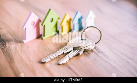 Silver Keychain in front of colourful miniature symbol of houses laying on the wooden surface Stock Photo