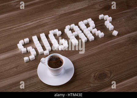 Word SUGAR with question mark made of sugar cubes with cup of espresso Stock Photo