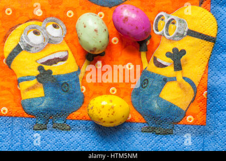 M&S chicky choccy speckled eggs, milk chocolate eggs with a speckled candy shell, on serviette with Minions - Minions juggling with them for Easter Stock Photo