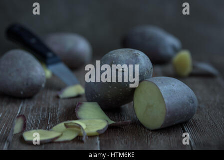 fresh potato tuber and cut the pieces with a knife on a wooden table in rustic style Stock Photo