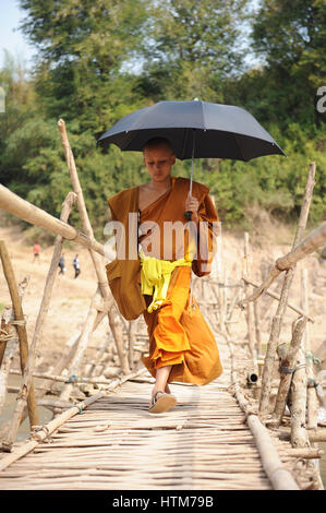 Monk crossing the bridge in Luang Prabang Stock Photo - Alamy