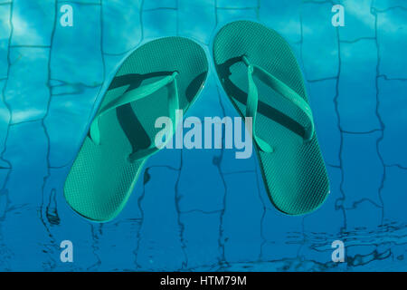 blue flip-flops floating in a swimming pool, a top view. Stock Photo