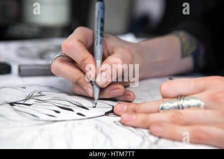 Girl tattoo artist draws a sketch. Close-up of hands Stock Photo