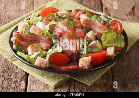 Mix salad of fried bacon, tomato, croutons and lettuce close-up on a plate on a table. horizontal Stock Photo