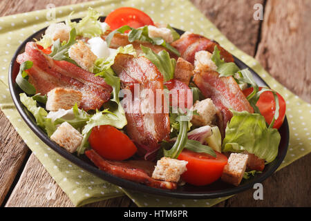 Salad of fried bacon, tomato, croutons and mix of lettuce close-up on a plate on a table. horizontal Stock Photo