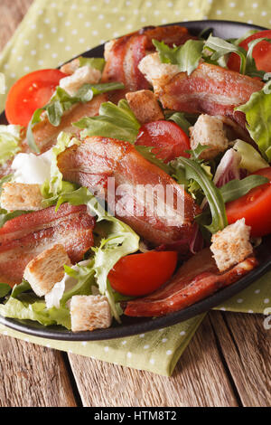Delicious salad of bacon, tomato, croutons and lettuce close-up on a plate. vertical Stock Photo