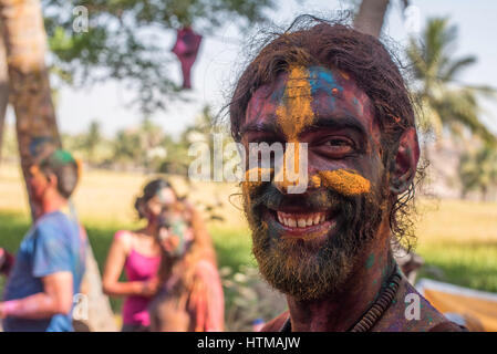 Man smiling at the camera whilst celebrating Holi in Hampi Stock Photo