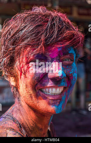 Paint covered face of young smiling woman enjoying Hoi in Hampi Stock Photo