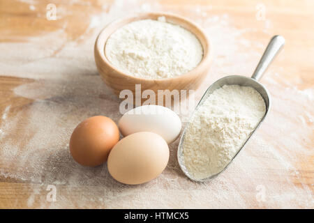 White flour and eggs on wooden table. Stock Photo