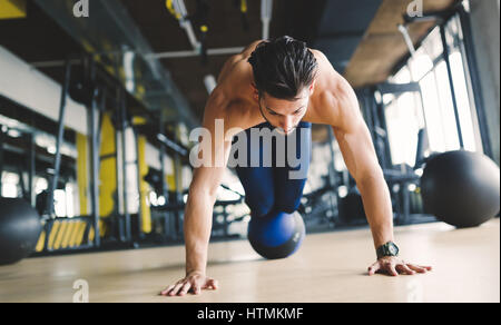 Sporty athlete doing push ups in gym during workout Stock Photo