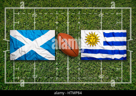 Scotland vs. Uruguay flags on green rugby field Stock Photo