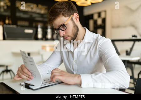 Businessman wearing glasses choosing from menu in restaurant Stock Photo