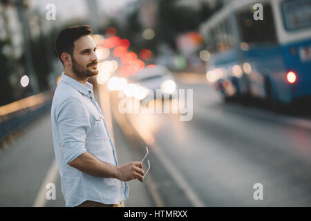 Aided by neon and city lights a male is walking home in city Stock Photo