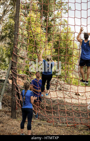 People climbing a net during obstacle course in boot camp Stock Photo