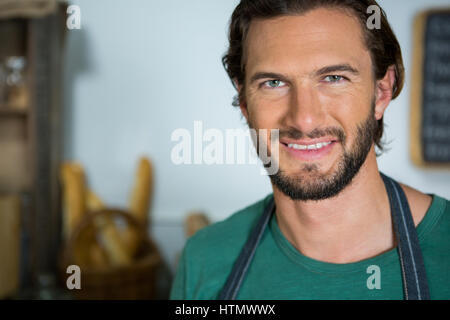 Portrait of smiling male staff standing with arms crossed in bakery shop Stock Photo