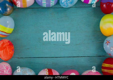 Various Easter eggs forming frame shape on wooden surface Stock Photo