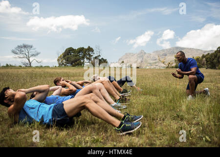 Fit people performing crunches exercise in bootcamp Stock Photo