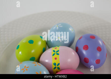 Painted Easter eggs arranged in plate on white background Stock Photo